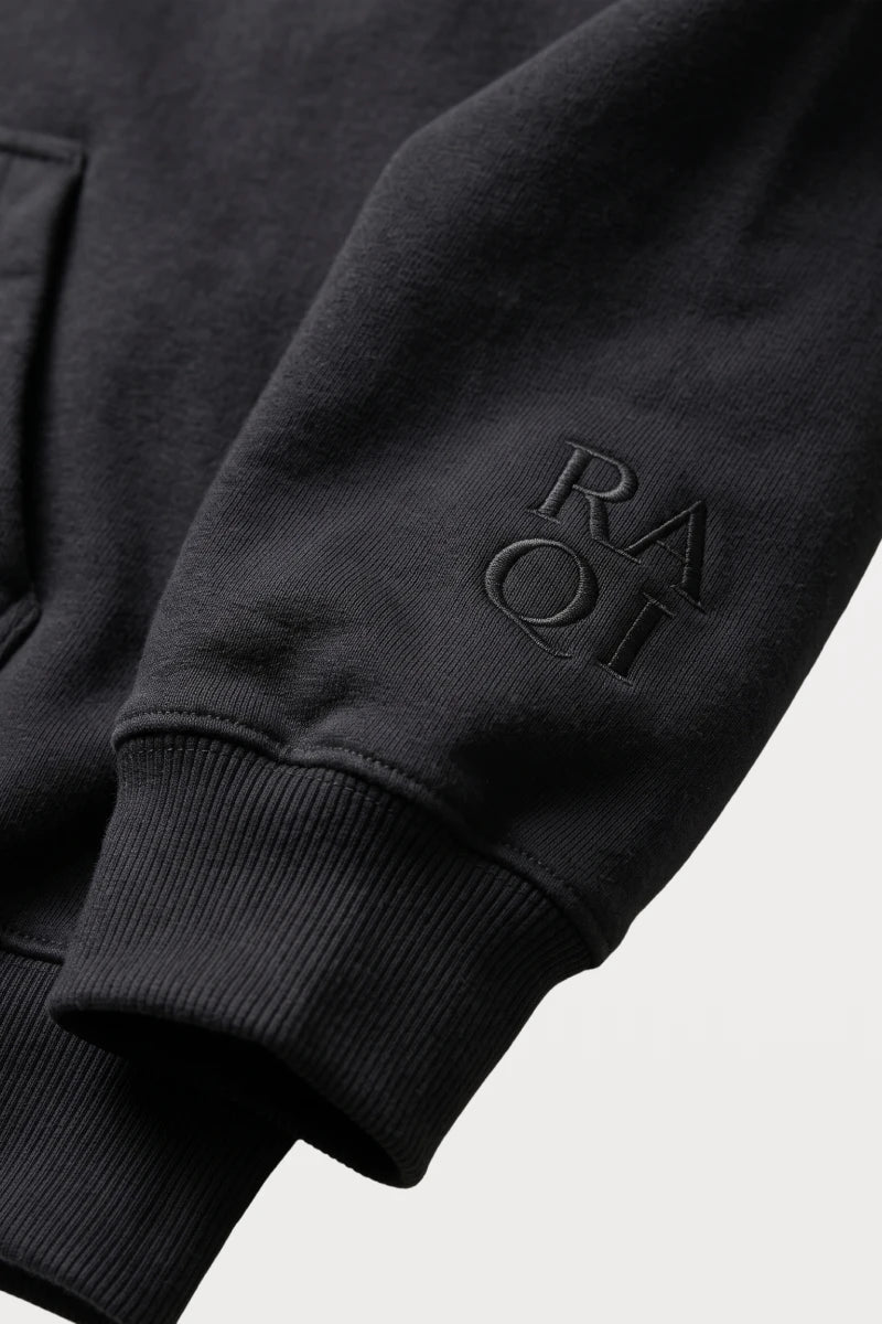 RAQI black pullover hoodie sleeve featuring a subtle tonal embroidered logo and ribbed cuff detail