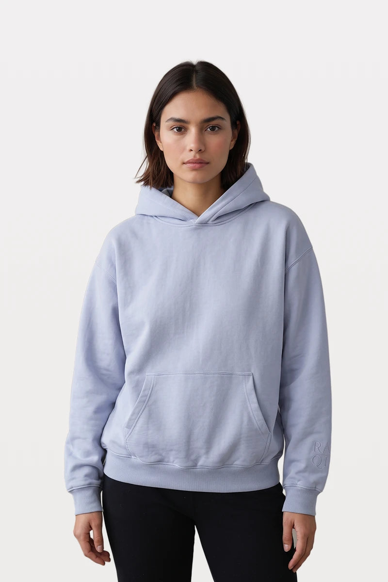 Model wearing a RAQI sky blue pullover hoodie with a kangaroo pocket and ribbed cuffs against a neutral background.